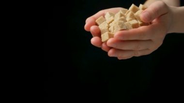 Eller işlenmemiş kamış şekeri, siyah arkaplan, yavaş çekim, metin için boşluk dolduruyor