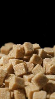 Kahverengi kamış şeker küpleri yığının üzerine düşüyor, makro yavaş çekim