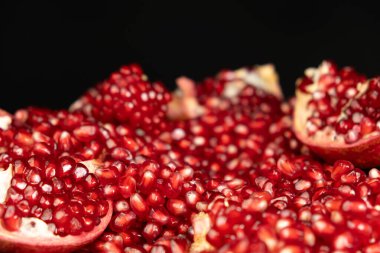 Pomegranate background, lots of peeled pomegranates and seeds, black background. clipart