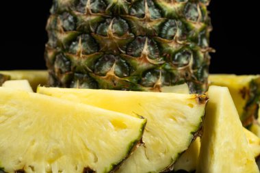 Tüm ananası parçalayıp siyah bir arka planda yakın plan çekimde parçalara ayrılmış.