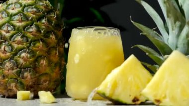 Ananas suyu sıçraması, yavaş çekim. Taze ananas parçaları bir bardak meyve suyuna düşer..