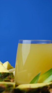 Ananas suyu bardakta, taze ananas meyvesinin yanında.