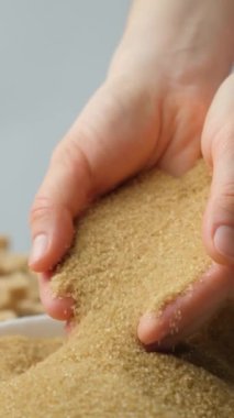 Eller kristal kamış kahverengi rafine edilmemiş sağlıklı demerara şekeri, dikey ağır çekim.