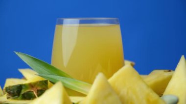 Ananas suyu bardakta, taze ananas meyvesinin yanında.