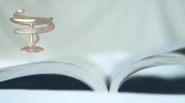 Tıbbın sembolü yılanlı bir kase ve sayfaları yavaşça çeviren bir kitaptır.