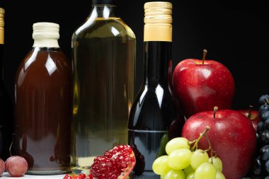 Different types of vinegar. Pomegranate, apple and balsamic vinegars in bottles. clipart