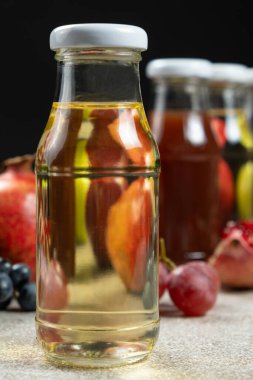 Fruit vinegars in glass bottles among fruits clipart