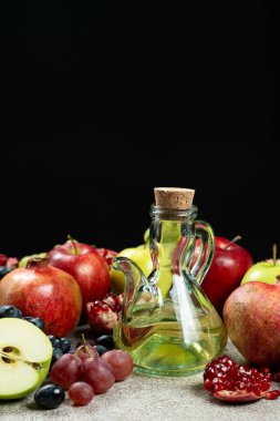 Cam sirke kabında sirke. Meyvelerin arasında siyah arka planda..