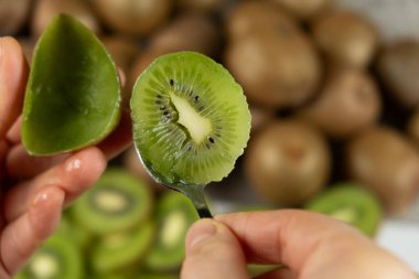 Taze olgun kivi meyvesini kaşıkla soyma süreci.