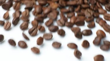 Kafeinsiz kahve çekirdekleri beyaz arka planda, yavaş çekim makrosu.