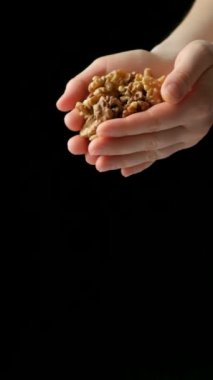 Bir avuç taze ceviz çekirdeği, ellerden dökülen fındıklar dikey ağır çekimde