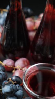 Şişe içinde kırmızı şarap sirkesi ve taze üzümler arasında sirke tabağı..