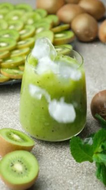 Buz küpleri yeşil kiviye düşüyor. Naneli smoothie yavaş çekim.