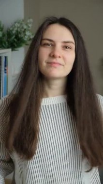 30 yaşında mutlu bir kadın gülümsüyor, göz kırpıyor. Makyajsız doğal güzellik. Dikey video.