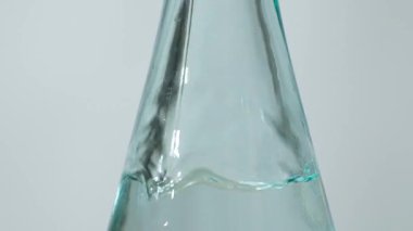 Beyaz damıtılmış sirke, cam kasenin içine yavaş çekimde dökülür. Temiz sıvıda kabarcıklar.
