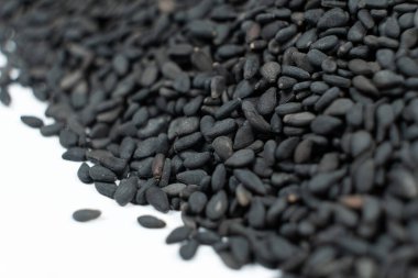 Siyah organik susam tohumları beyaz arkaplanda yakın plan.