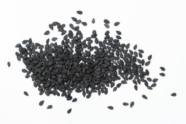 Siyah susam tohumları beyaz arka plan makro üst görünüm üzerine dağılmış.