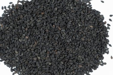 Siyah susam tohumları beyaz arka plan makro üst görünüm üzerine dağılmış.