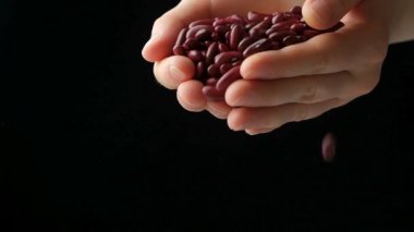 Eller pişmemiş kırmızı fasulye döküyor. Yavaş çekimde yakın çekim, mesaj için yer..