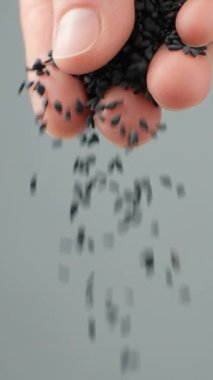 El, siyah susam dökerken yavaş çekim dikey