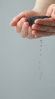 Siyah susam döken eller dikey yavaş çekim, metin için yer.