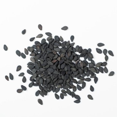 Siyah susam tohumları beyaz arka plan makro üst görünüm üzerine dağılmış.