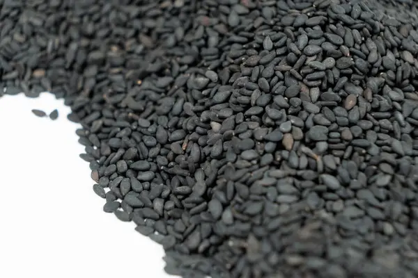 Siyah organik susam tohumları beyaz arkaplanda yakın plan.