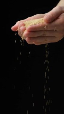 Eller organik amaranth tanelerini yavaş çekimde dikey olarak döküyor..