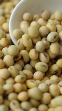 Çiğ soya fasulyesi kaşık makro dikey ağır çekimde dökülüyor.
