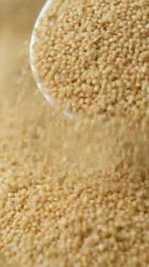 Organik amaranth taneleri kaşık dikey yavaş çekimde dökülüyor.