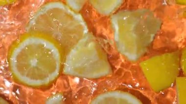 Suda taze limon dilimleri, biraz su, taze turuncu arka plan, üst manzara, yavaş çekim