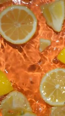 Yarım limon ve taze limon dilimlerinin sulu arkaplanı su, üst görünüm, dikey yavaş çekim