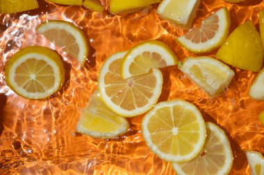 Suda taze limon dilimleri, biraz su, taze turuncu arka plan, üst manzara..
