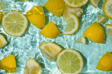 Turkuaz narenciye arkaplanı yüzen sarı limon parçalarıyla tazeleniyor.