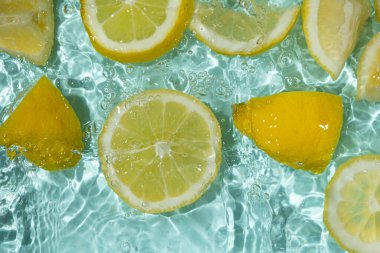 Turkuaz narenciye arkaplanı yüzen sarı limon parçalarıyla tazeleniyor.