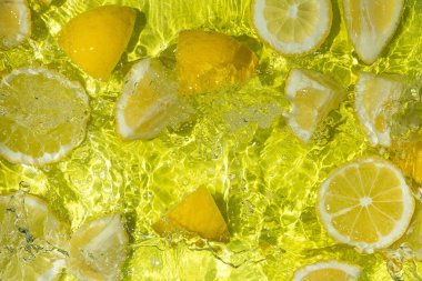 Hareketli suda yüzen canlı sarı limon parçaları.