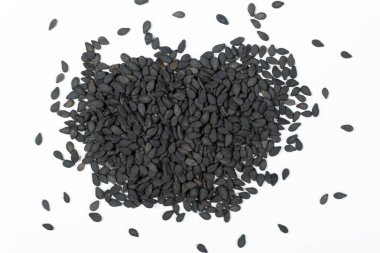 Siyah susam tohumları beyaz arka plan makro üst görünüm üzerine dağılmış.