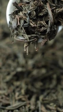 Siyah çay yaprakları kaşıkta, makro yavaş çekim dikey çekim