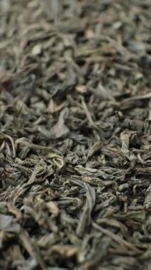 Siyah büyük yaprak çay yaprakları dökülüyor, makro doku, dikey ağır çekim.