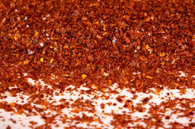 Beyaz arka plana serpilmiş parlak kırmızı biber tozu.