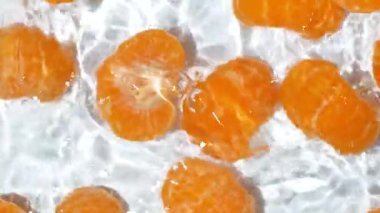 Taze soyulmuş mandalinalar berrak sulara dökülüyor..