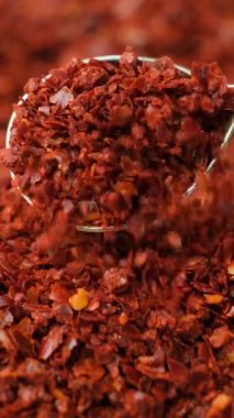 Ezilmiş kırmızı kırmızı biber, doğal baharatlı, dikey ağır çekimde..