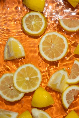 Yarım limon ve taze limon dilimlerinin sulu arkaplanı..