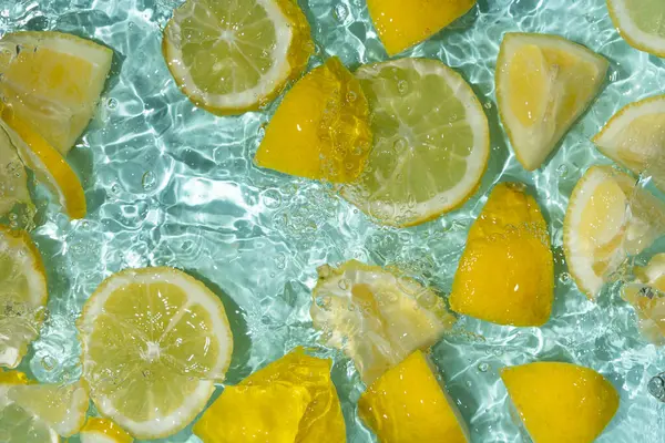 Turkuaz narenciye arkaplanı yüzen sarı limon parçalarıyla tazeleniyor.