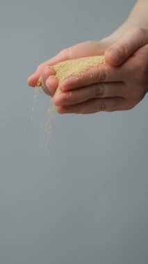 Eller organik amaranth tanelerini yavaş çekimde dikey olarak döküyor..