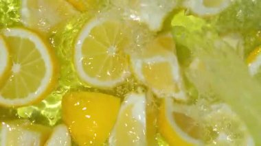 Suda taze dilimlenmiş meyve limonlarının yavaş hareket etmesi, limonata yapıyor.