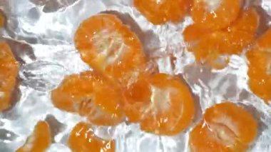 Taze soyulmuş mandalinalar berrak sulara dökülüyor..