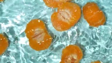 Suda soyulmuş taze mandalina, su sıçratma, üst manzara, yavaş çekim.