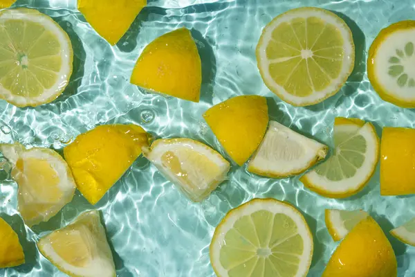 Turkuaz narenciye arkaplanı yüzen sarı limon parçalarıyla tazeleniyor.