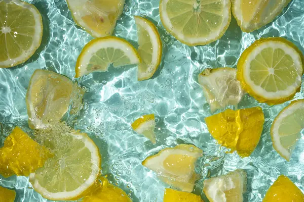 Turkuaz narenciye arkaplanı yüzen sarı limon parçalarıyla tazeleniyor.